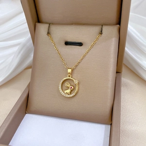 Close-up of a gold rabbit and moon pendant with red crystal eyes in a beige gift box