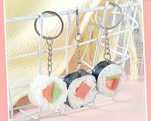 Dettaglio di portachiavi sushi in PVC realistici appesi a un cesto di metallo bianco