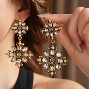 Gros plan de boucles d'oreilles vintage dorées avec cristaux et perles blanches