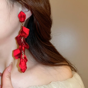 Detail showing long red petal tassel clip-on earrings on a model's neck and jawline