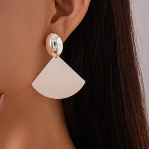 Close-up of geometric fan-shaped earrings with silver oval metal and white texture