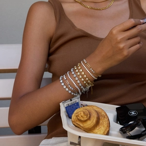 Close-up of stacked gold and silver bracelets with zircon heart links on a wrist