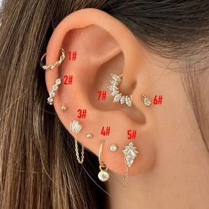 Gold stud earring set with sparkling zircons worn by a model in a luxury layered style