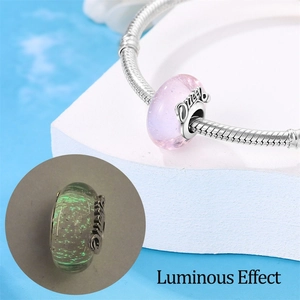 Luminous Queen charm detail showing pink glass bead and glowing green effect in dark