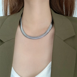 Flat herringbone snake chain necklace in titanium steel worn with an olive green blazer