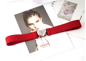 Détail d'une ceinture élastique rouge avec une boucle en métal argenté en forme de cœur