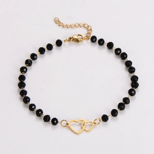 Detailed shot of gold chain bracelet with black faceted beads and double heart pendant