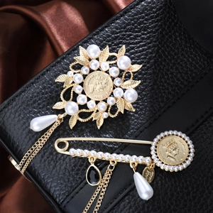 Detail of vintage gold pearl brooches with leaf pattern and elegant chain elements