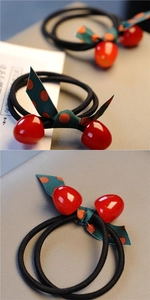 Close-up of red cherry hair tie with green polka dot ribbon and high elastic band