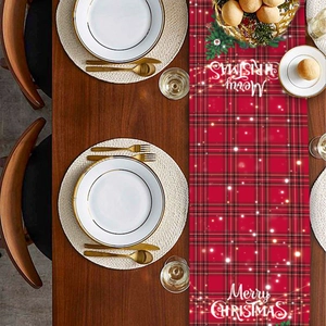 Detail of red plaid Christmas table runner with Merry Christmas text on wood table