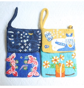 Detailed close-up of four handmade wool felt coin purses with floral embroidery and beads
