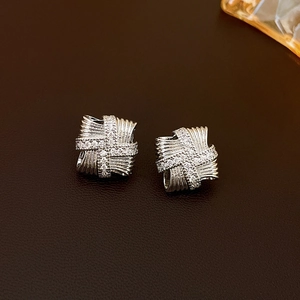 Close-up of square silver earrings with cubic zirconia and woven ribbon texture detail