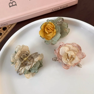 Detailed view of fabric camellia flower hair clips in pink, yellow and green colors
