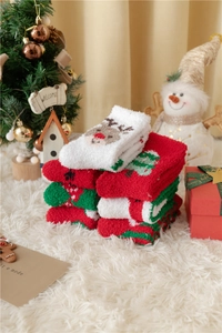 Détail de chaussettes de Noël en polaire corail avec motifs de cerfs et sapins aux tons de fête