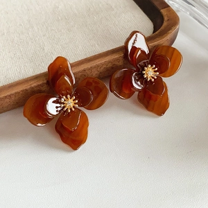 Vue détaillée des boucles d'oreilles fleurs en résine ambrée avec détails en métal doré
