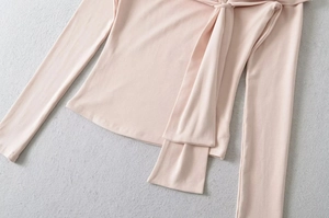 Detail of pink long sleeve knit top featuring decorative front ribbon bow tie design