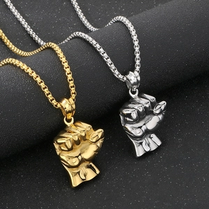 Macro view of solid hip hop fist pendants in gold and silver on black background
