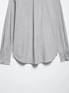 Detail view of light gray long sleeve shirt featuring curved hem and buttoned cuffs