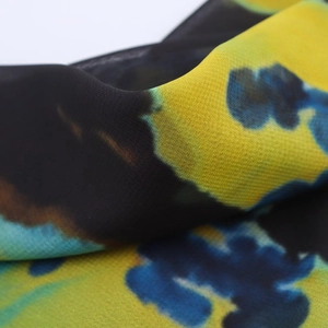 Macro view of lightweight semi-sheer fabric with abstract yellow and blue tie-dye pattern