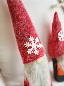 Close-up of plush red Christmas gnome wine bottle cover with snowflake and faux fur