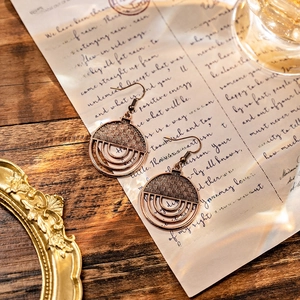Close-up of bohemian bronze earrings featuring woven texture and concentric circles
