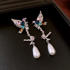 Detail of vintage bird earring featuring colorful rhinestones and a teardrop pearl drop