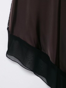 Dettaglio dell'abito midi in raso marrone scuro con orlo in chiffon nero e pizzo
