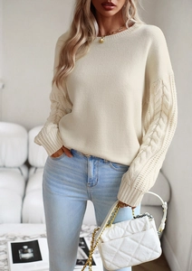 Dettaglio del maglione beige girocollo con maniche decorative a treccia e consistenza morbida