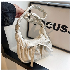 Detail of cream pleated shoulder bag with a bow and ruffled adjustable strap