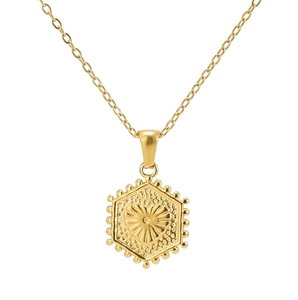 Macro shot of 18K gold hexagonal pendant with sunburst heart pattern and beaded edge detail