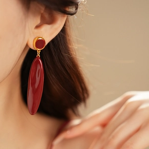 Vue rapprochée de boucles d'oreilles vintage ovales dorées et bordeaux sur mannequin