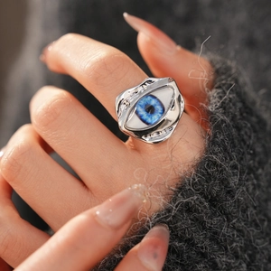Macro detail of irregular silver metal ring with a realistic blue evil eye centerpiece