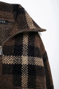 Close-up of brown and black plaid bomber jacket showing wool texture and silver zipper