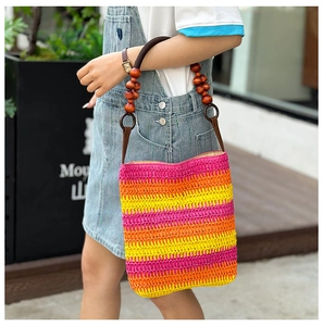 Detail of colorful rainbow straw tote bag featuring vintage wooden beads on a brown handle