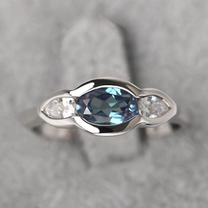 Minimalist geometric ring with oval sapphire-blue stone and teardrop accents in silver