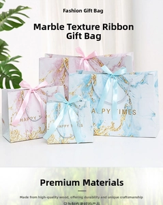 Detail view of marble pattern gift bags with golden letters and silk ribbon bow knots