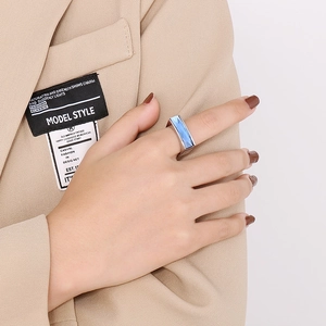 Detail of square blue gemstone ring with silver metal band worn on a beige suit
