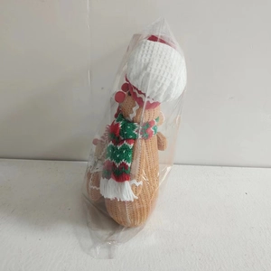 Close-up of a knitted gingerbread man wearing a red and green scarf and white hat