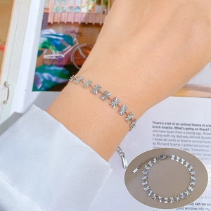 Minimalist silver clover leaf stainless steel chain bracelet worn on a woman's wrist