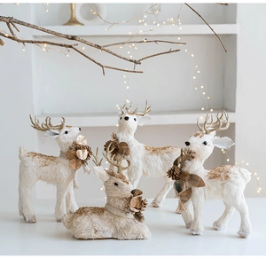 Close-up of white and gold plush reindeer statues with warm festive string lights