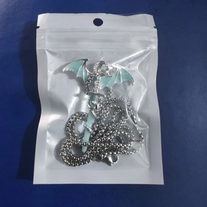 Detailed view of silver dragon-wrapped sword pendant with light green glow-in-the-dark finish