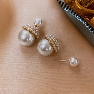 Détail macro de boucles d'oreilles rétro françaises à double perle sur fond de soie