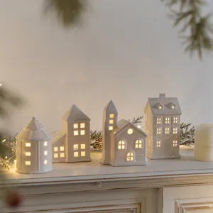 Set of four white ceramic Christmas house candle holders with warm LED glowing windows