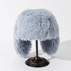 Detail view of light blue-grey plush earflap hat on a black vintage metal stand