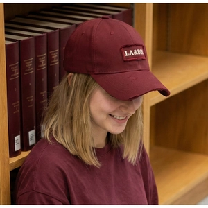 Close-up of distressed brim and embroidered LA&DH patch on a vintage burgundy baseball cap