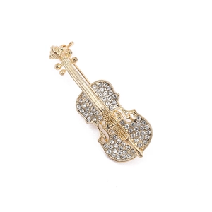 Dettaglio di una spilla a violino in lega dorata con strass trasparenti incastonati