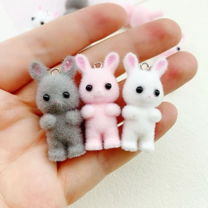 Macro view of mini flocked rabbit pendants in grey, pink, and white for DIY crafts