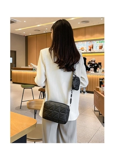 Gros plan sur le sac matelassé noir avec bandoulière large et mini pochette ronde