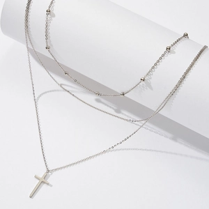 Detail view of layered S925 sterling silver necklaces featuring cross pendant and bead chain