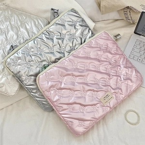 Close-up of quilted bow laptop sleeves in pink, silver and white satin finish